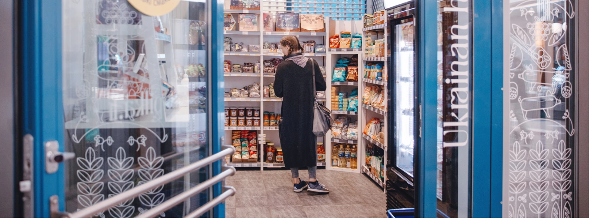 Nainen katselemassa ja tutkimassa ukrainalaisia ruokia Sopilkan myymälässä